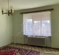 A bright room in a family house with a carpet, radiator, and curtains.