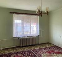 A room in a family house with a radiator, carpet, and curtains on the window.