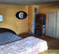 Rustic room with a tiled stove and beds in a family house.