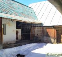 The courtyard of a family house in Osturňa with a wooden shelter and a snow-covered plot.