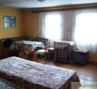 A cozy room with wooden decor, windows, a table, and a bed in a family house.