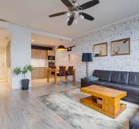 Living room in a three-room apartment with a wooden decor floor and a leather sofa.
