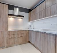A kitchen in a 3-room apartment with a kitchen unit featuring a wooden decor and a white countertop.