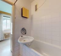 Bathroom with a bathtub and white tiles in a 2-room apartment.