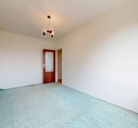 A room in a 2-bedroom apartment with a carpet and patterned curtain.