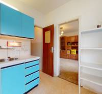 A kitchen in a 2-room apartment with blue cabinets and a white shelf.