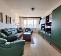 Living room in a two-room apartment with green sofas and a floor with a wood decor.