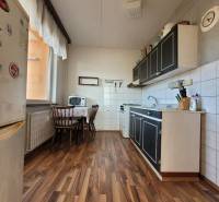 A kitchen in a 2-room apartment with a wooden decor floor and a dining table.