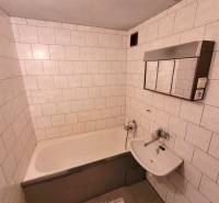 A bathroom with a bathtub and white tiles in a 2-room apartment.