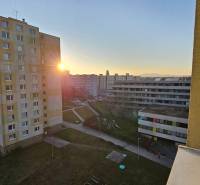 View from a studio apartment in Topoľčany, panel buildings, sunset, and a children's playground.