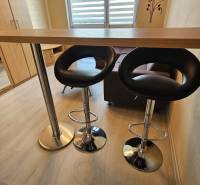 Studio apartment with a counter, chairs, and flooring with a wood finish.