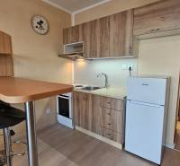 A kitchenette in a studio apartment with a wooden decor, table, chairs, kitchen cabinets.