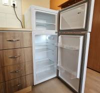 Studio apartment with a kitchenette and an open refrigerator, floor with wooden decor.