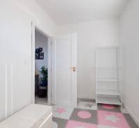 A children's room in a three-room apartment with white walls and a colorful floor.