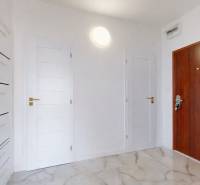 Hallway in a 3-room apartment with white doors and storage cabinets.