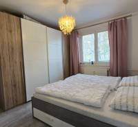 A bedroom in a 2-room apartment with a large wardrobe and a bed, floor with a wooden decor.