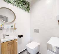 A bathroom in a 3-room apartment with a washing machine, sink, mirror, and decorative elements on the wall.