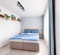 A bedroom in a 3-room apartment with a double bed, blue curtains, and a wooden decor floor.