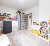Children's room in a three-room apartment with a wooden decor floor, shelves with books, toys.