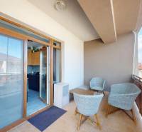 A balcony with rattan furniture in a 3-room apartment, Veľký Biel, Lipova, with access to the kitchen.