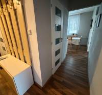 A hallway in a 3-room apartment with a wooden decor floor and a table by the window.
