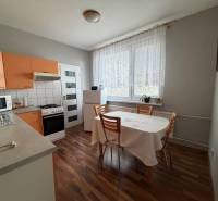 A kitchen with a dining table and a wooden decor floor in a 3-room apartment.