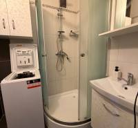 Bathroom with a washing machine, shower, and sink in a 3-room apartment.