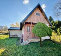 A family house in Šarišské Čierne with wooden cladding and a grassy garden.