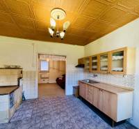 A kitchen in a family house with older furniture and tiles, a tiled stove.
