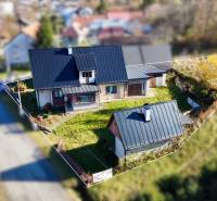A family house in Šarišské Čierne with a landscaped garden and a metal roof in a street development.