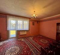 Living room in a family house with a red carpet, simple curtains, and light.