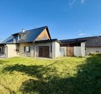 A family house in Šarišské Čierne with a lawn, a modern roof, and partially wooden walls.