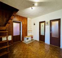 Interior of a family house with a wooden decor floor, staircase, and three doors.