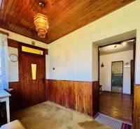 Wooden paneling on the walls and ceiling, colorful chandelier, table in a family house.