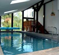 Interior of a holiday apartment with a wood-patterned floor and an indoor pool.