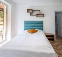 Single bed in a holiday apartment with a wooden decor floor and a large window.