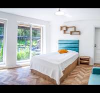 A bright room with a bed, large windows, and a wooden decor floor in a vacation apartment.