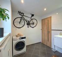 A bathroom in a 2-room apartment with a bicycle, a washing machine, and tiles.