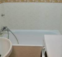 Bathroom with a bathtub, washing machine, and white tiles in a 2-room apartment.