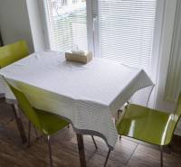 A dining room with an open window, two chairs, and a wooden-patterned floor in a two-room apartment.