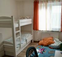 A room in a 2-room apartment with a bunk bed, a desk, and a wooden decor floor.