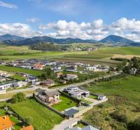 An aerial view of family houses in Dolný Kalník surrounded by green hills.