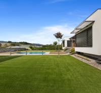 A family house in Dolný Kalník with a lawn, terrace, and pool against a scenic backdrop.