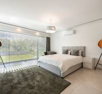 A bright bedroom in a family house with a carpet, a large window, and decorative lamps.