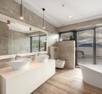 A bathroom in a family house with a bathtub, two sinks, and a floor with a wooden decor.