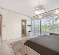 Bright bedroom with large windows and gray carpet in a family house.