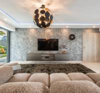 Living room with a beige sofa, TV on the wall, and a striking light fixture in a family house.