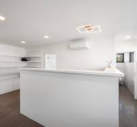 A minimalist interior in a family house with white walls, a floor with a wood decor, and air conditioning.