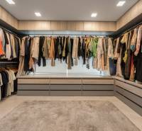 A wardrobe in a family house with a lot of clothes, cabinets, and a window seat.