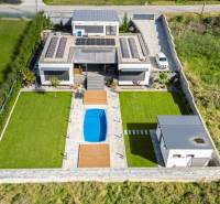 A family house in Dolný Kalník with solar panels and a swimming pool on a landscaped plot.